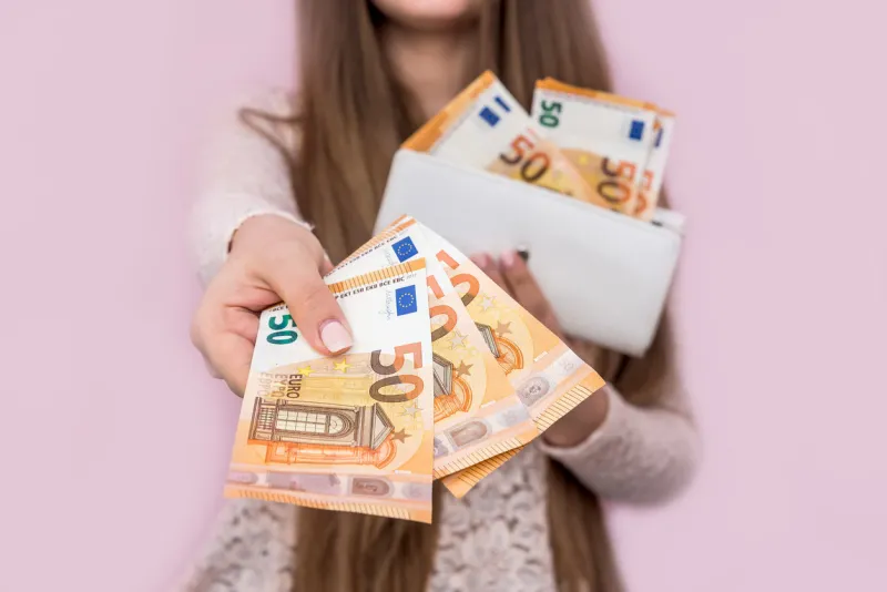 female hands giving euro banknotes on pink background