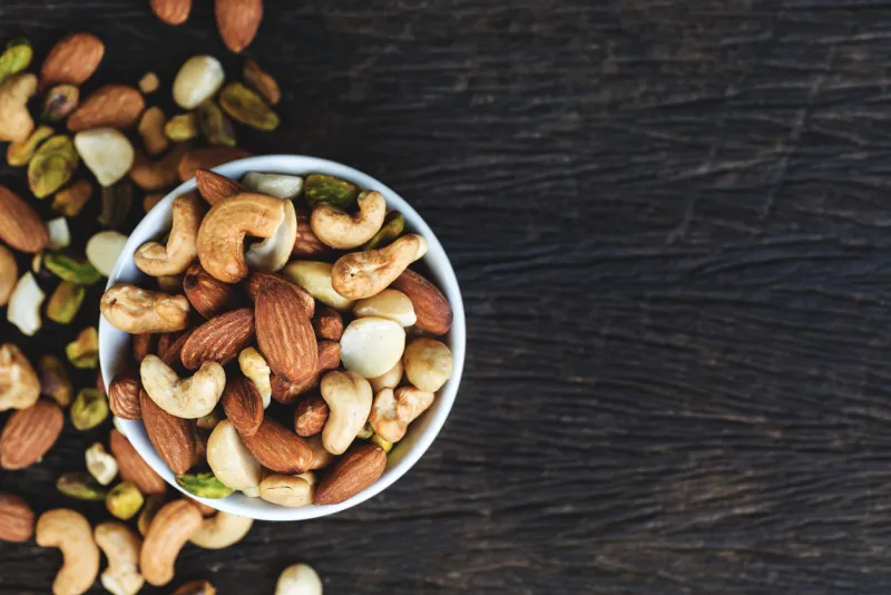 healthy food and snack   mixed nuts in white ceramic bowl from above, walnut, pistachios, almonds, hazelnuts and cashewsnn