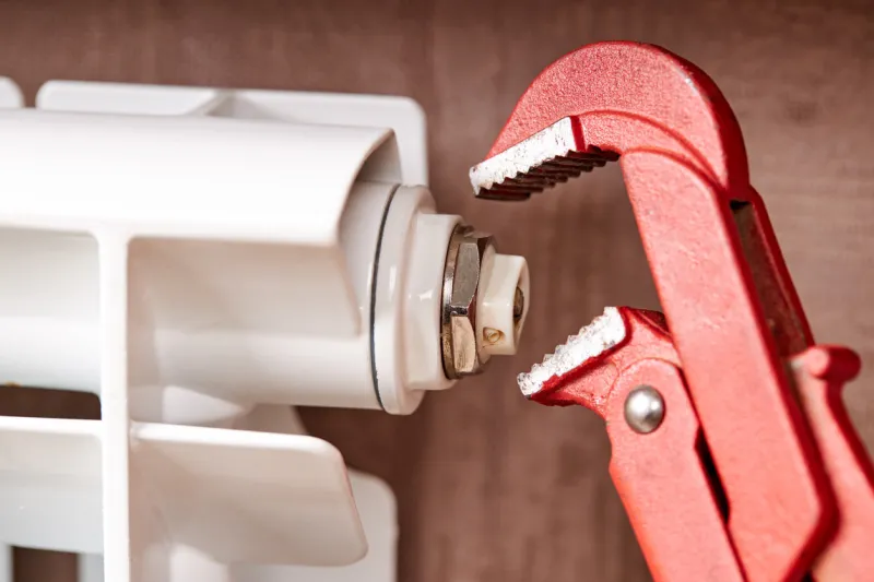 male technician worker repairing aluminum water radiator indoors plumber repairman concept water heating system diagnose