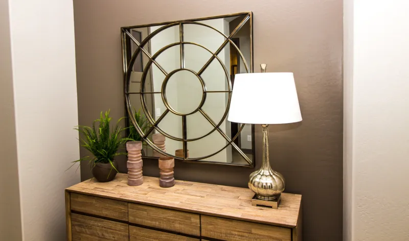 contemporary wall mirror over wooden bedroom dresser with lamp & decorator items