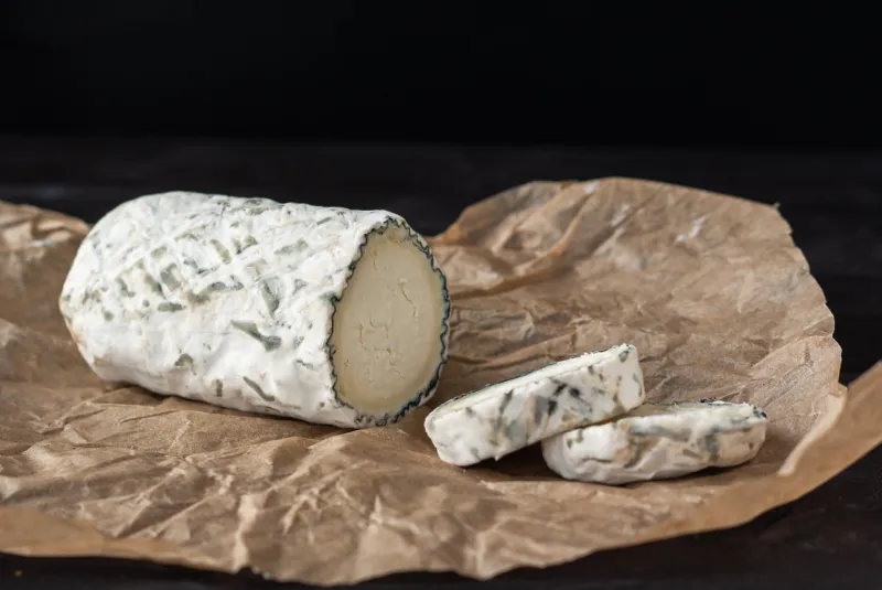 delicious goat chevre cheese slices on a dark wooden background
