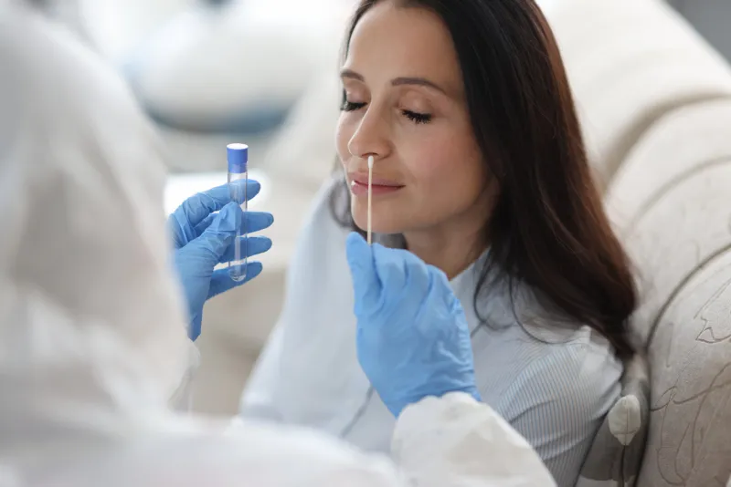 doctor laboratory assistant in protective suit takes swab from nose of sick patient at home laboratory tests for coronavirus concept