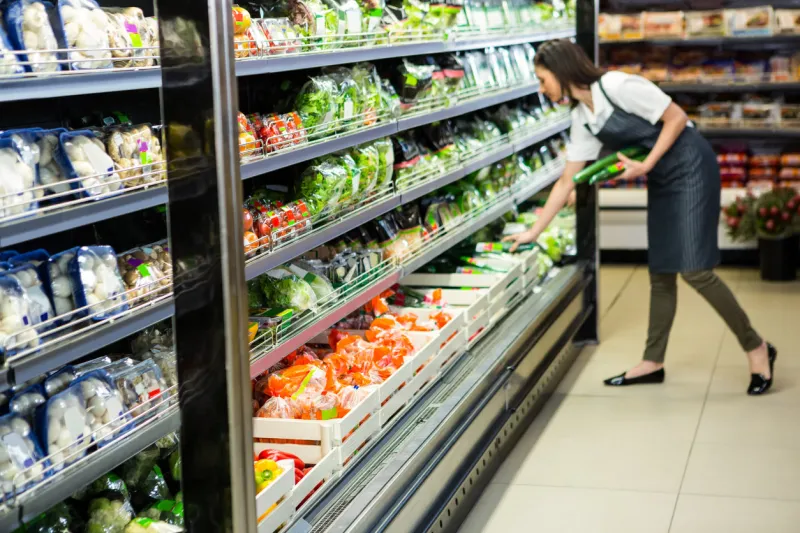 portrait of a smiling worker taking a vegetables in supermarket