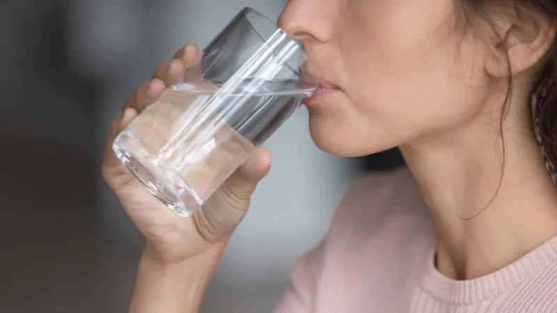 close up profile thirsty woman drinking enjoying pure mineral water, preventing dehydration, holding glass, healthy lifestyle and good habit concept, natural beauty, skin and health care