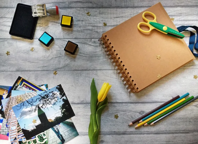 scrapbook accessories spread on the table  scrapbook album, photos, stamps, scissors and crayons