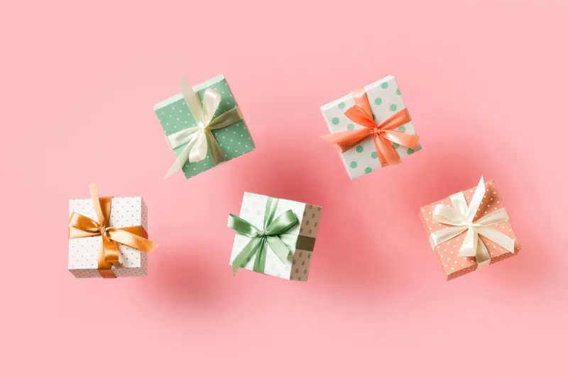 polka dot pattern gift box with ribbon falling on pink background, levitation, creative pastel