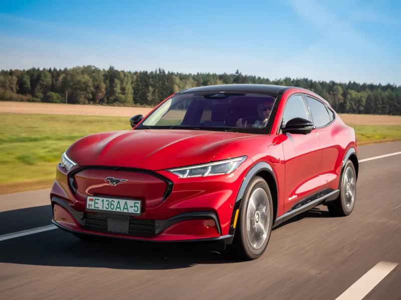 minsk, belarus - september 10, 2021  all-electric bright red ford mustang mach-e drives on a highway during a sunny day