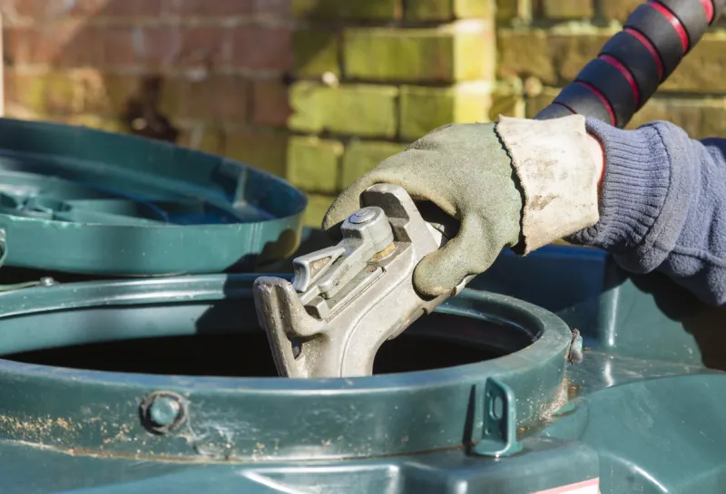closeup of man filling a bunded oil tank with domestic heating oil (kerosene) at a house in rural england, uk
