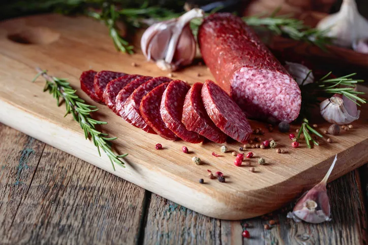 smoked salami on a old wooden table sausages with rosemary , garlic and pepper