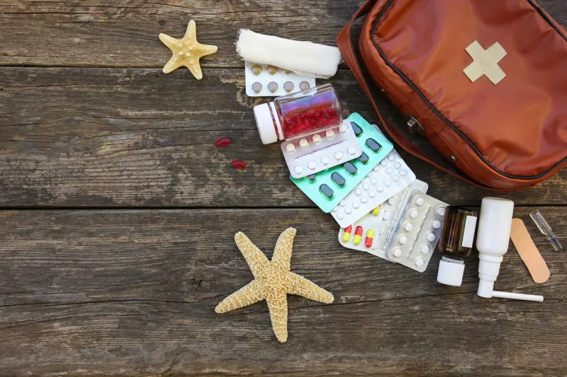 first aid kit on old wooden background concept of medication required in journey top view flat lay