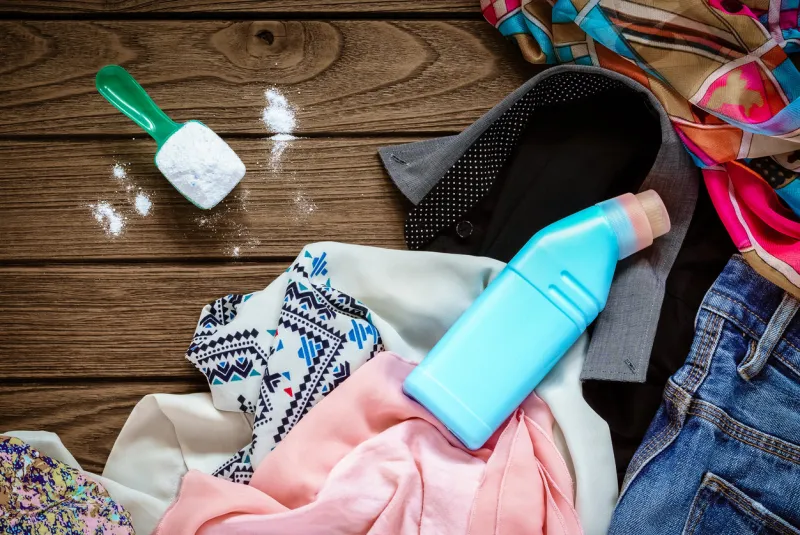 pile of clothes with detergent and washing powder, top view