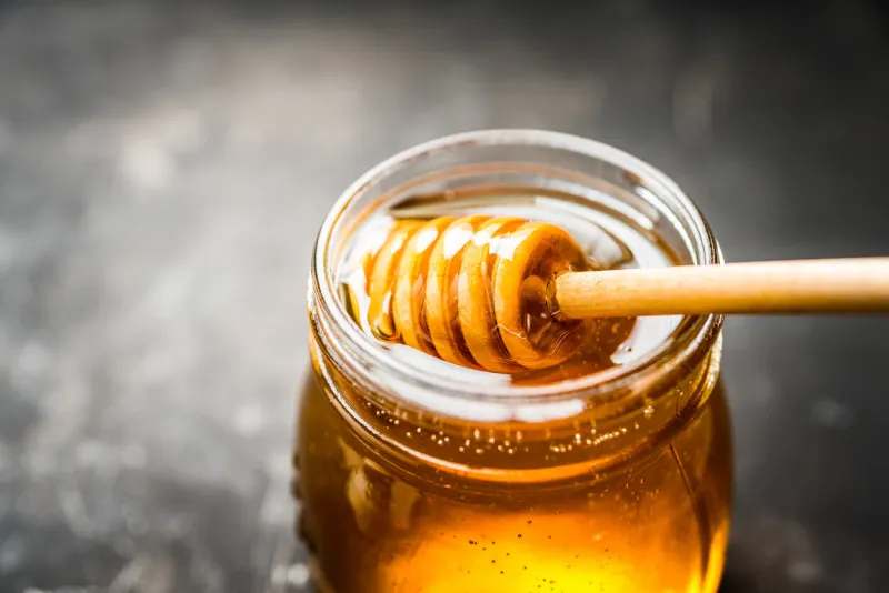 jar with freshly harvested liquid honey on the old wooden table selective focus