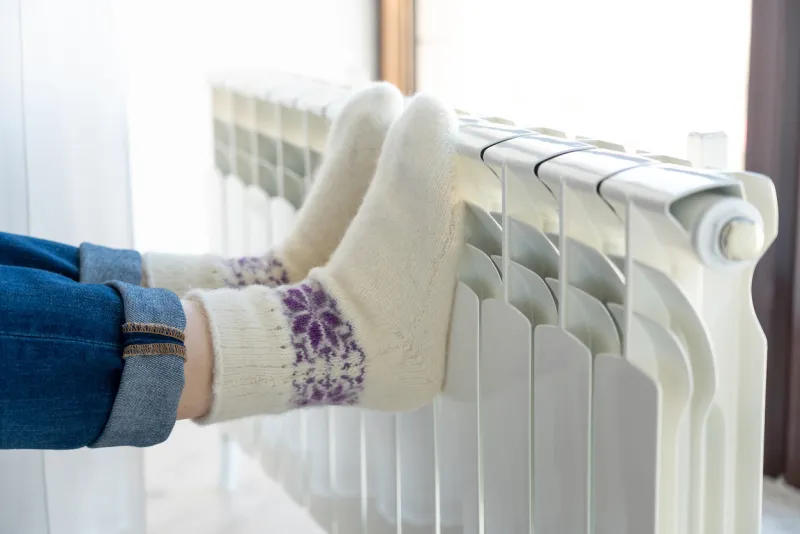 woman warming up with feet on heater wearing woolen socks