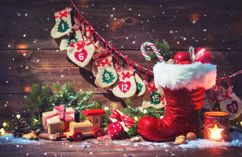 christmas background advent calendar and santa's shoe with gifts on rustic wooden background