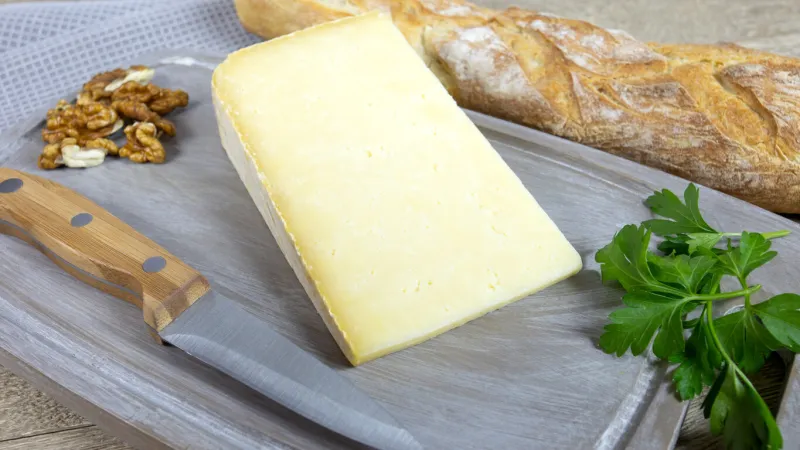 hard cantal a wooden board with baguette of bread