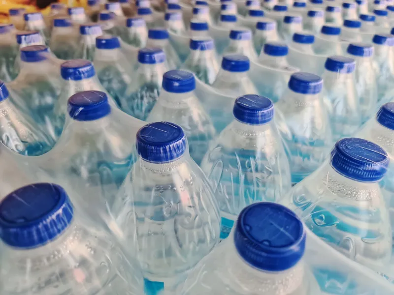 large number of packed bottled drinking water with blue caps