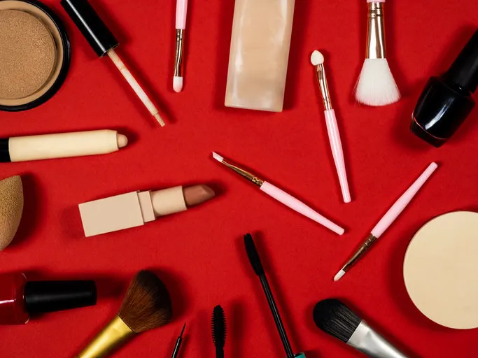 a set of decorative cosmetics lipstick, powder and makeup brush, foundation, cosmetic brush, eye concealer cosmetic set red background