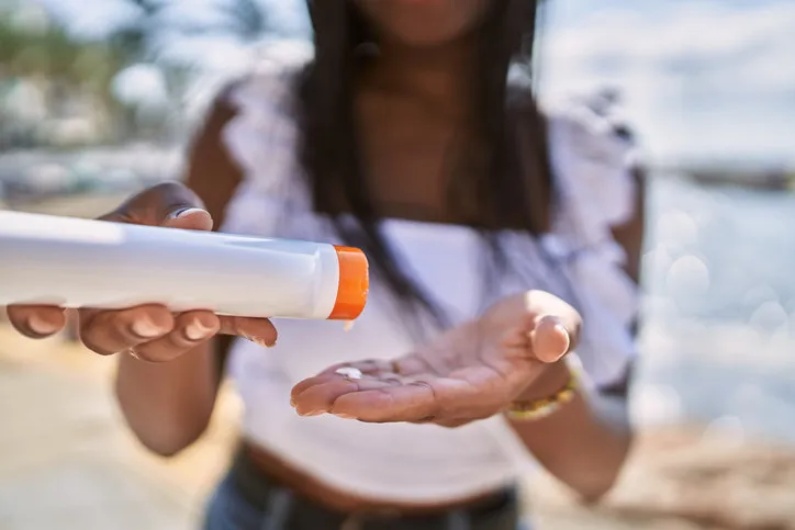 young african american girl using sunscreen lotion at the beach