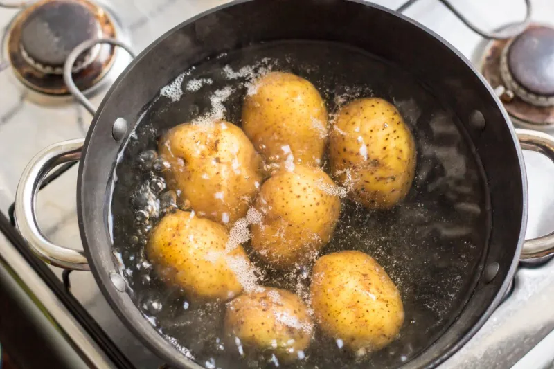 potatoes boiling in a saucepan on a gas hob