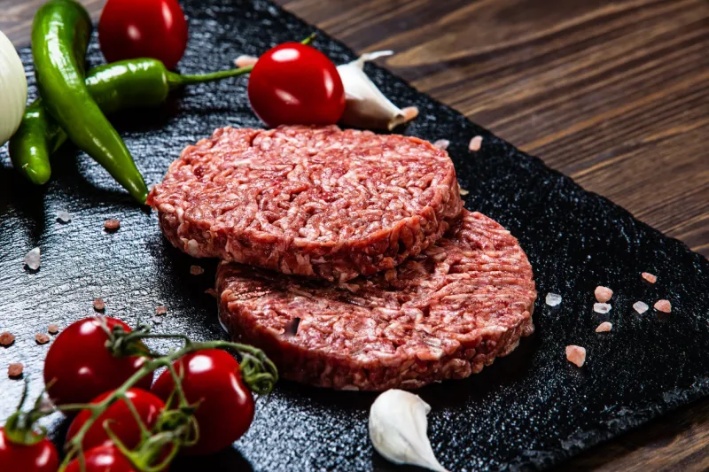 raw burger, bun and vegetables