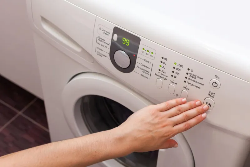 young woman or housekeeper select the program on washer