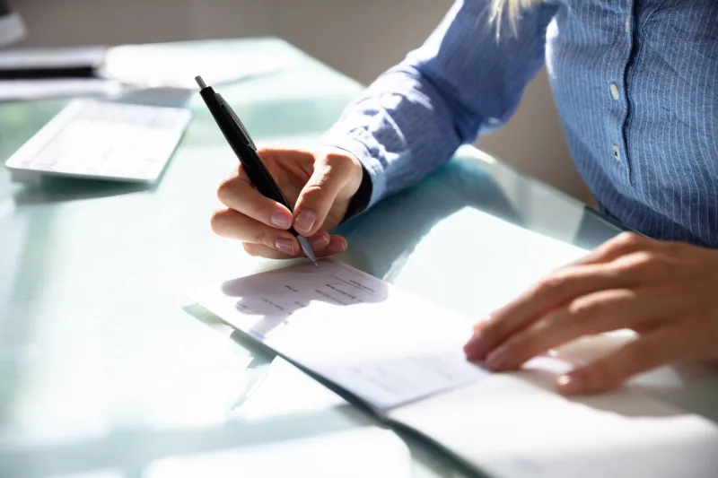 close-up of a businesswoman's hand signing cheque