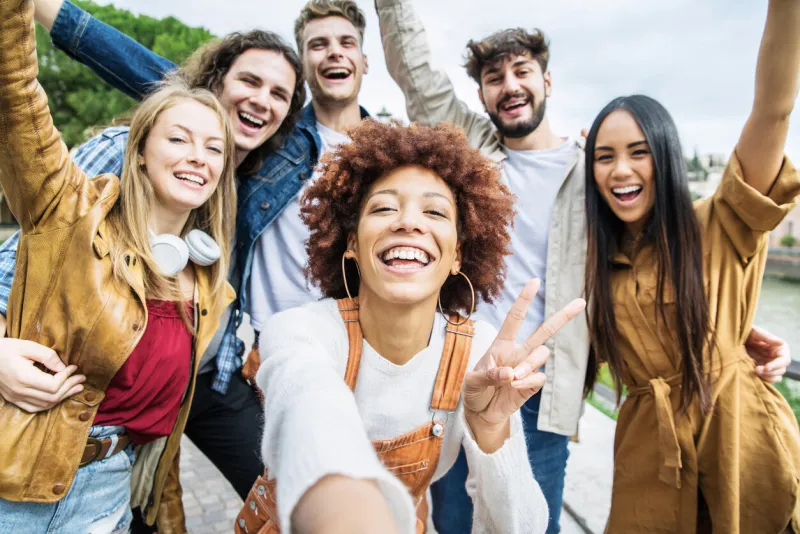 group of happy friends taking selfie pic outside - happy different young people having fun walking in city center - youth lifestyle concept with guys and girls enjoying day out together