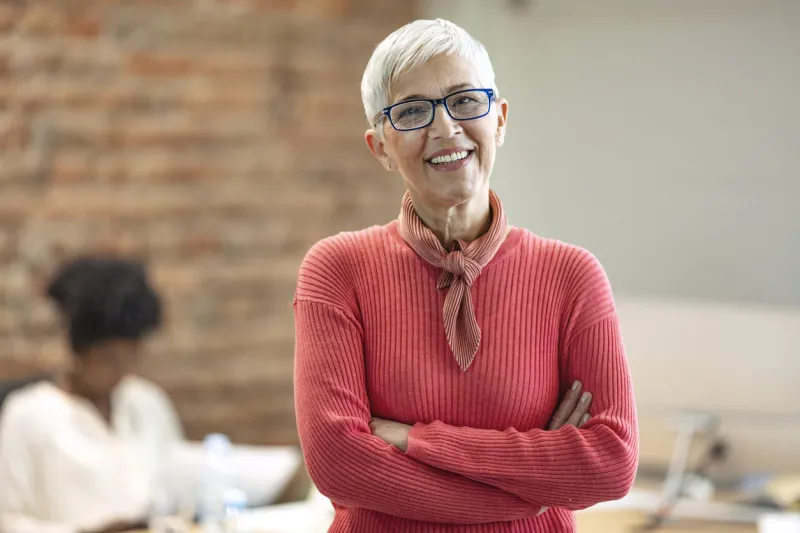 senior businesswoman in office pretty older business woman, successful confidence with arms crossed in financial building cheerful attractive businesswoman crossing arms on chest and looking at camera