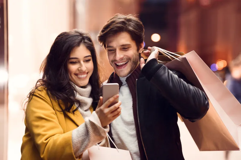 order clothes online couple after shopping in mall using phone to make purchases outdoors