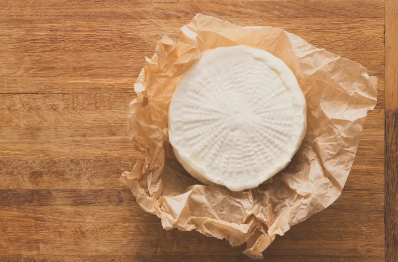 cheese wheel, fresh homemade indian paneer on wooden board, close-up, top view
