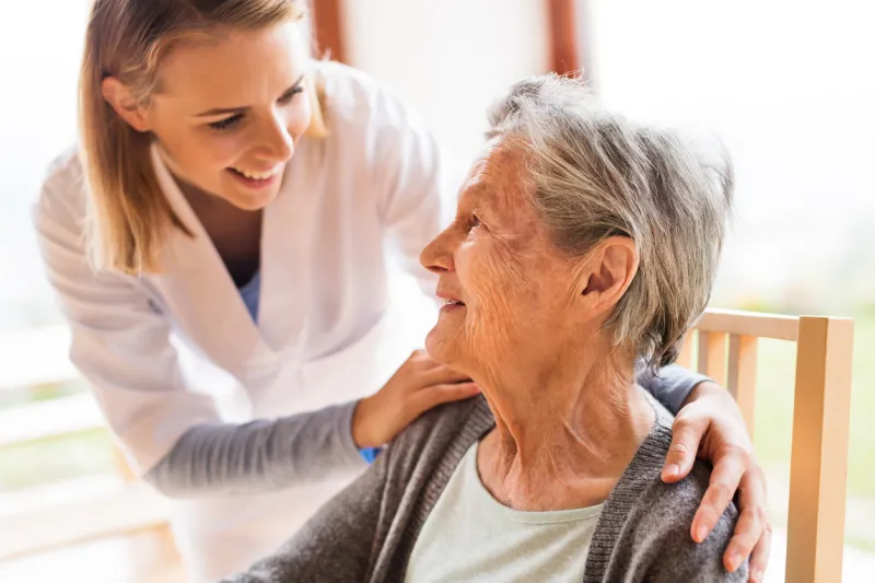 health visitor and a senior woman during home visit a nurse talking to an elderly woman