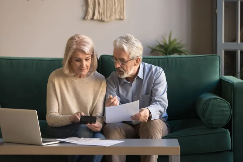 serious mature couple calculating bills to pay, checking domestic finances, middle aged family managing, planning budget, expenses, grey haired man and woman reading bank loan documents at home