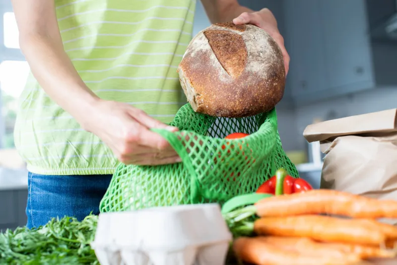 close up of woman unpacking local food in zero waste packaging from bag