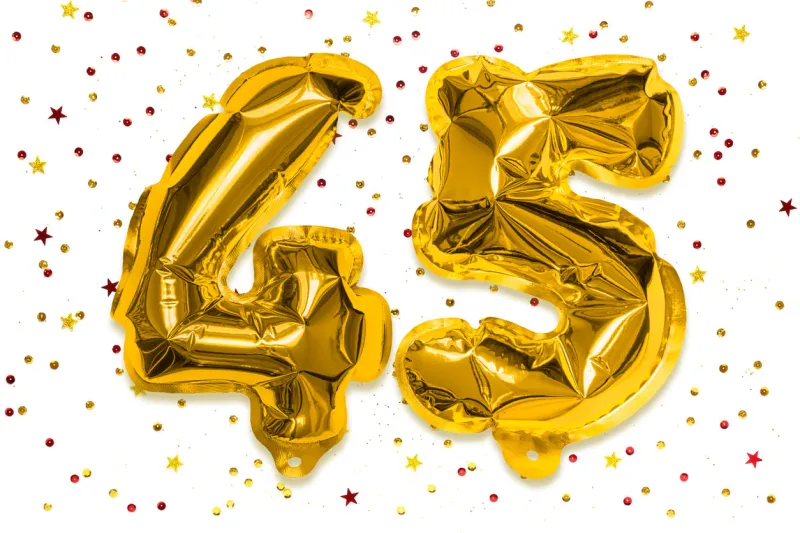 the number of the balloon made of golden foil, the number forty five on a white background with multicolored sequins birthday greeting card with inscription 45 anniversary concept