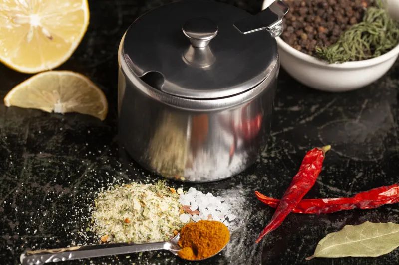 metal container for spices with assortment of spices for cooking on a black background,top view