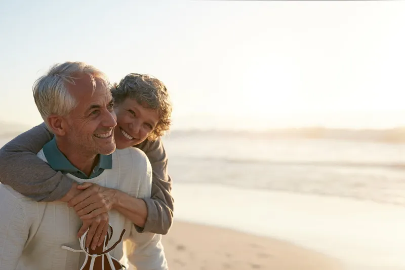 portrait of happy mature man being embraced by his wife at the beach senior couple having fun at the sea shore