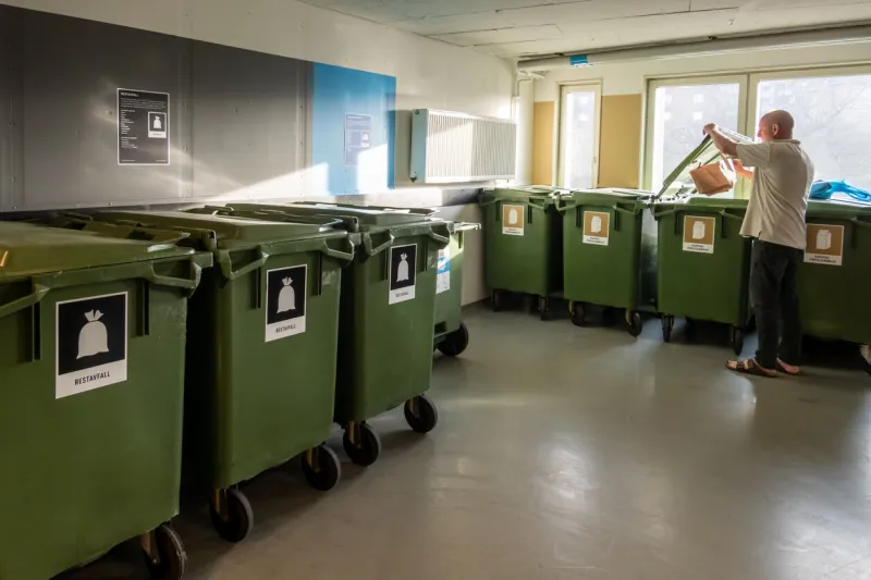stockholm, sweden a man throws garbage in a super clean and organised garbage room in a residential housing complexthe labels denote type of waste in swedish