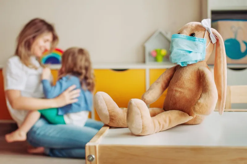 soft toy bunny on the table in the kids room defocused toddler daughter playing with mother stay home during quarantine virus outbreak concept