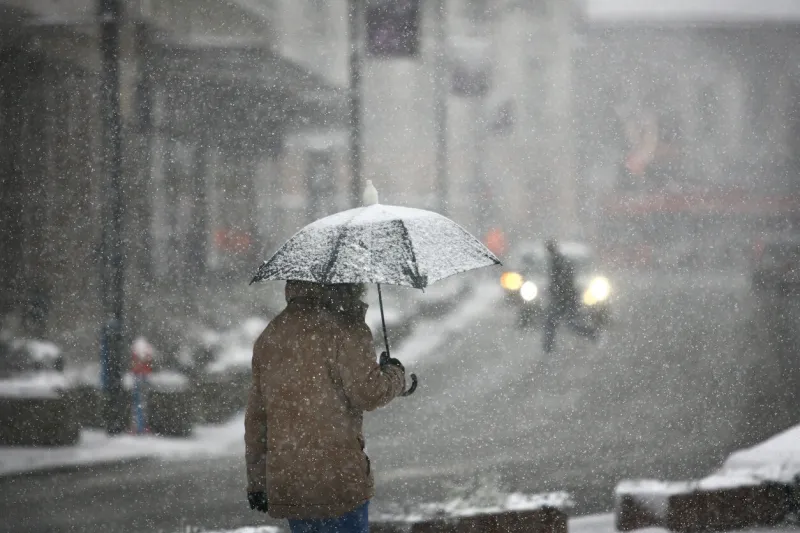 man with umbrella during snow storm in the street
