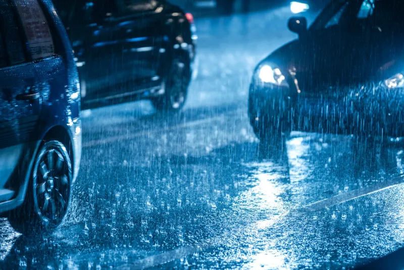 cars driving on wet road in the rain with headlights