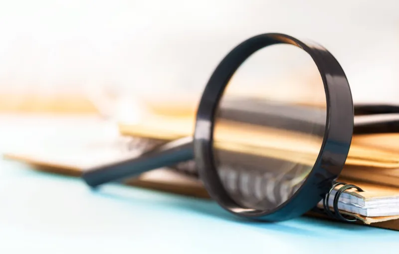 magnifying glass with notebooks and books on the table education concept