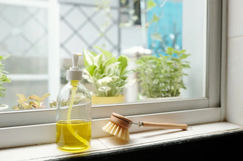 bottle of yellow dish soap and brush on window sill in kitchen