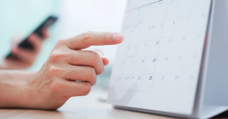 close up on employee man hand using finger pointing schedule (timetable) on calendar to make appointment meeting or manage timetable each day , life balance concept
