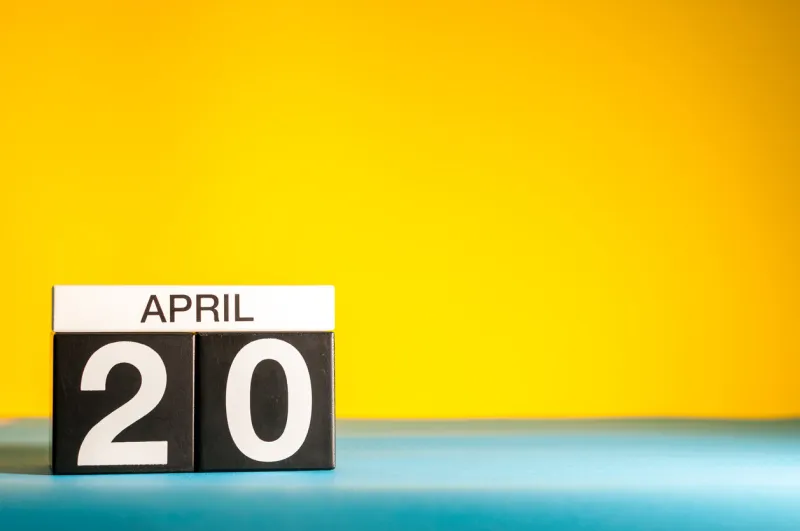 april 20th day 20 of april month, calendar on table with yellow background spring time, empty space for text