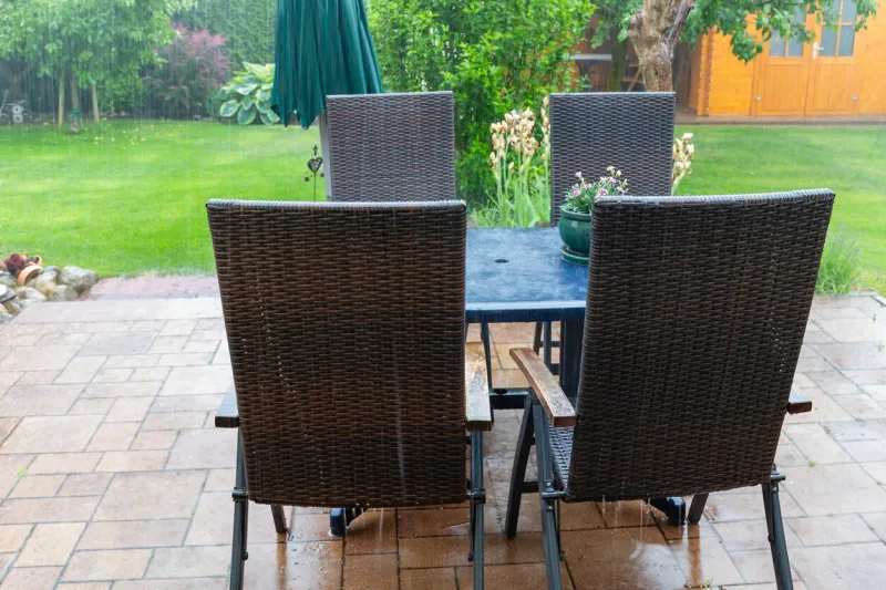terrace furniture in the summer rain, water flows from the table and chairs onto the terrace, heavy rain can be seen in the background, selective focus