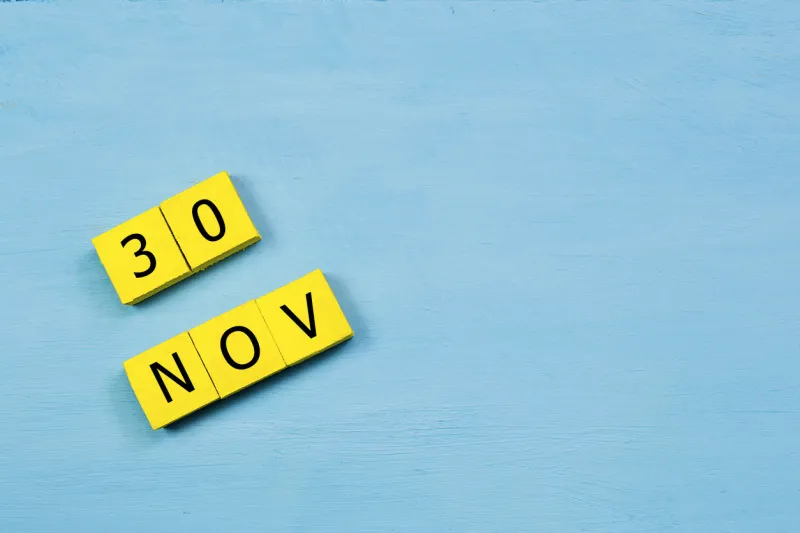 nov 30, yellow cube calendar on blue wooden surface with copy space
