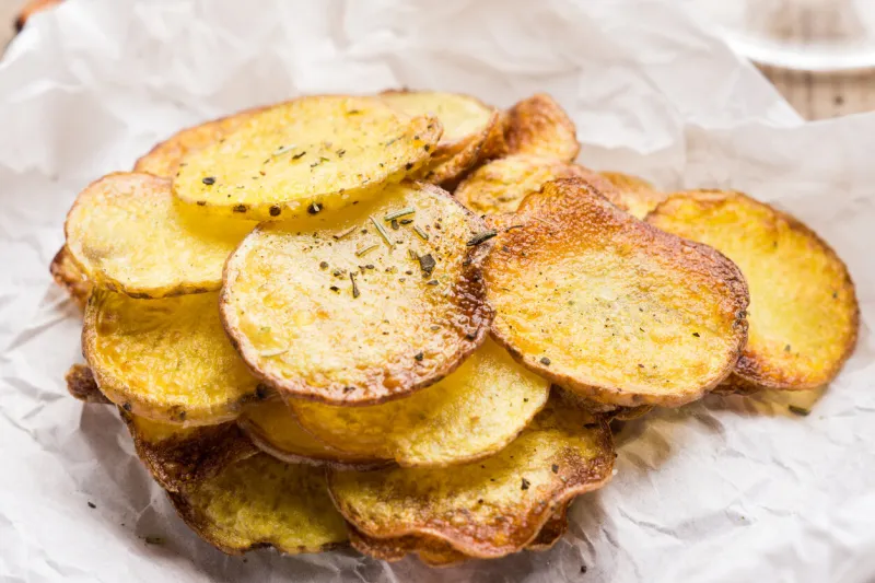 homemade potato chips with spices on the wooden table