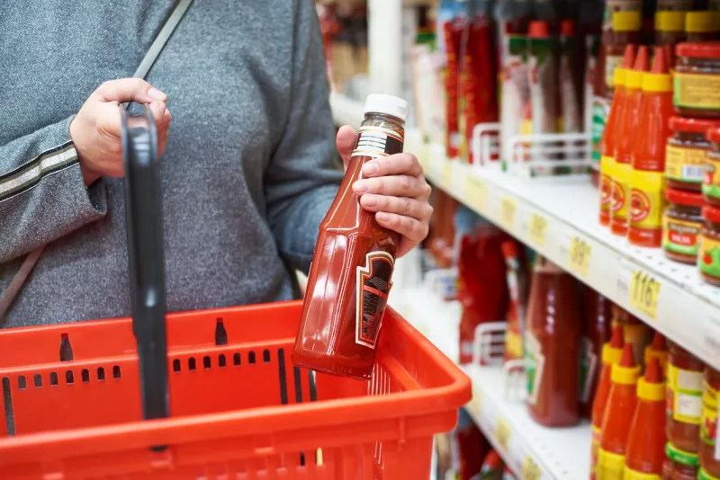 packing of tomato ketchup in hands and a shopping cart