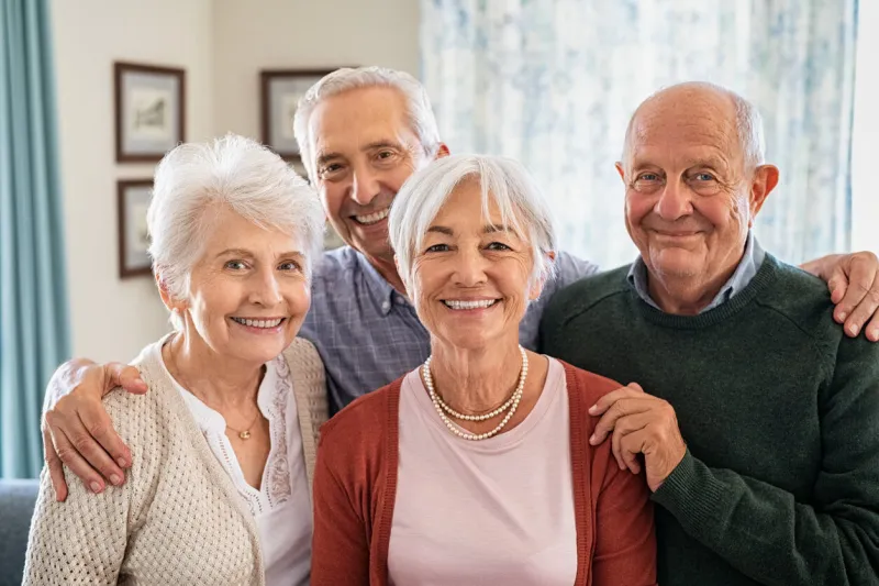 portrait of happy elderly people looking at camera at care centre cheerful senior man and beautiful old woman embracing and posing for a photo smiling seniors standing together with a big grin on their faces at nursing home