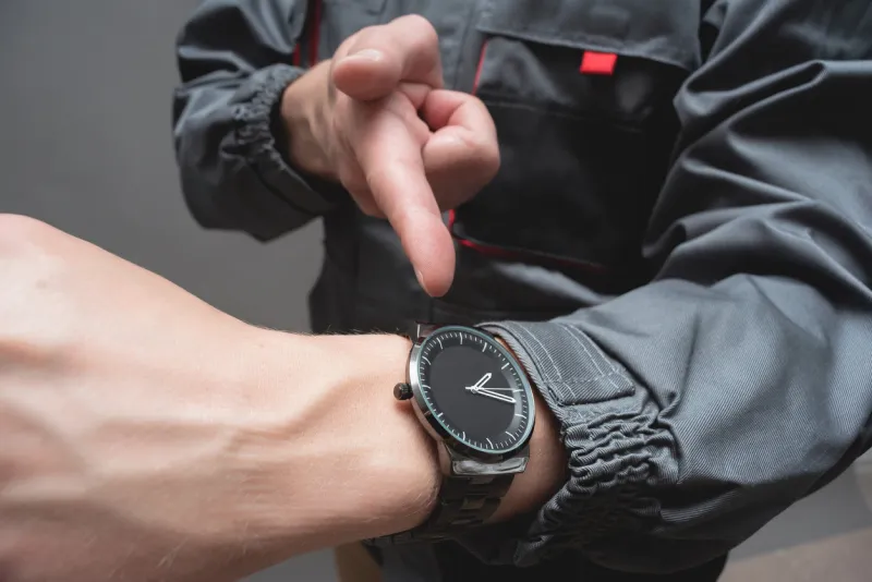 car service worker is pointing on the wrist watch on his hand close up fast service